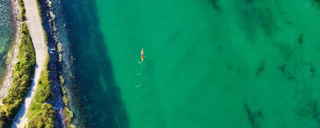 Aerial view of a canoe gliding through the tranquil waters of Hayle Estuary, showcasing the natural beauty of the area, and it's vital part to history of Hayle.