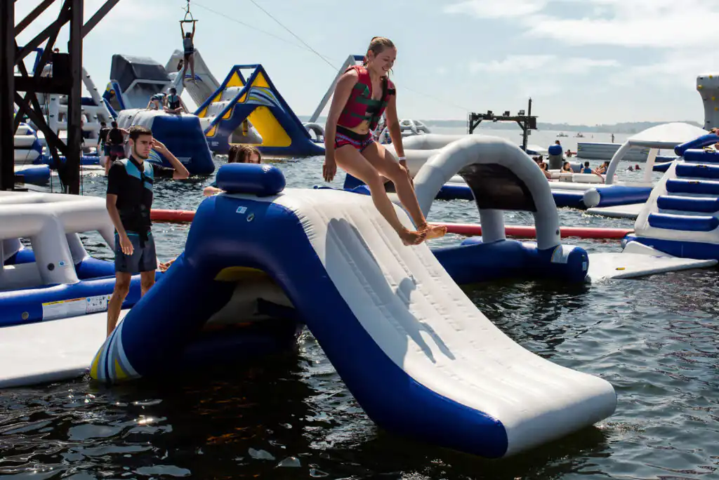 A woman slides down an inflatable water slide at a Cornish Aquapark, enjoying a fun day of adventure in Cornwall.