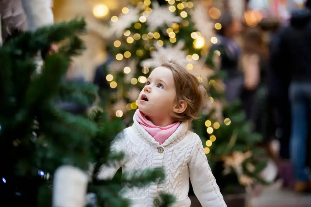 A little girl gazes up in wonder at a beautifully decorated Christmas tree in Cornwall.