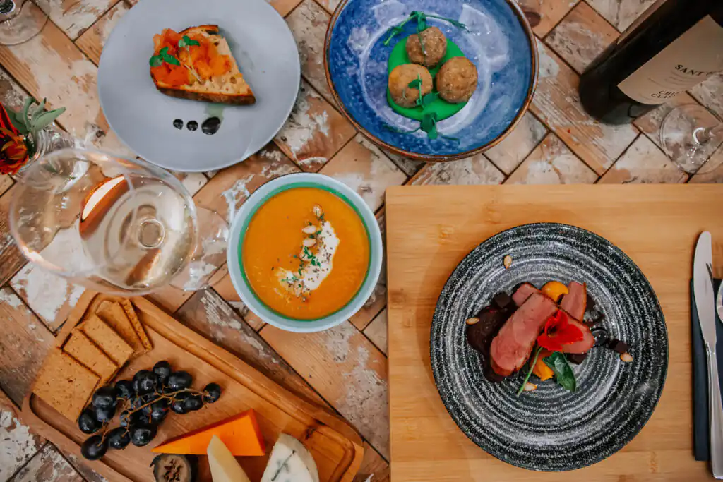 A beautifully set table featuring plates of delicious food and glasses of wine, perfect for private dining during holidays for large groups in Cornwall.