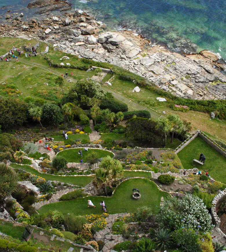 Scenic view of St Michael's Mount gardens near Marazion with lush greenery and the ocean in the background.