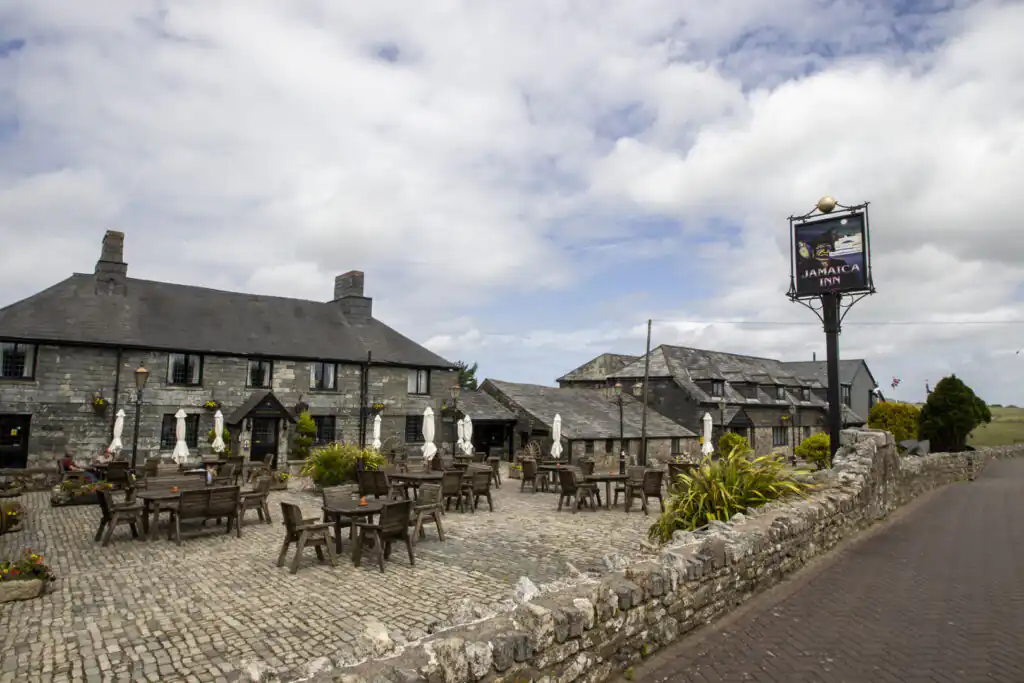Exterior of Jamaica Inn in Bude with stone architecture and outdoor seating area, a great stop off point on a car journey to Cornwall.