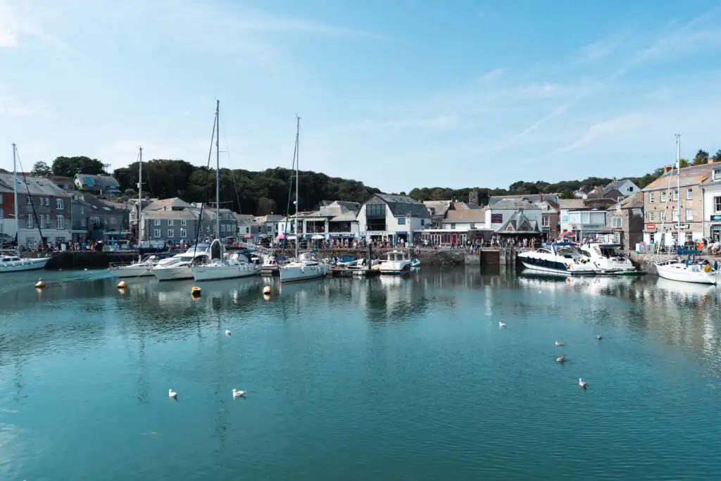 A clear blue sky dotted with fluffy white clouds above Padstow Harbour, highlighting a beautiful day for walking in Cornwall.