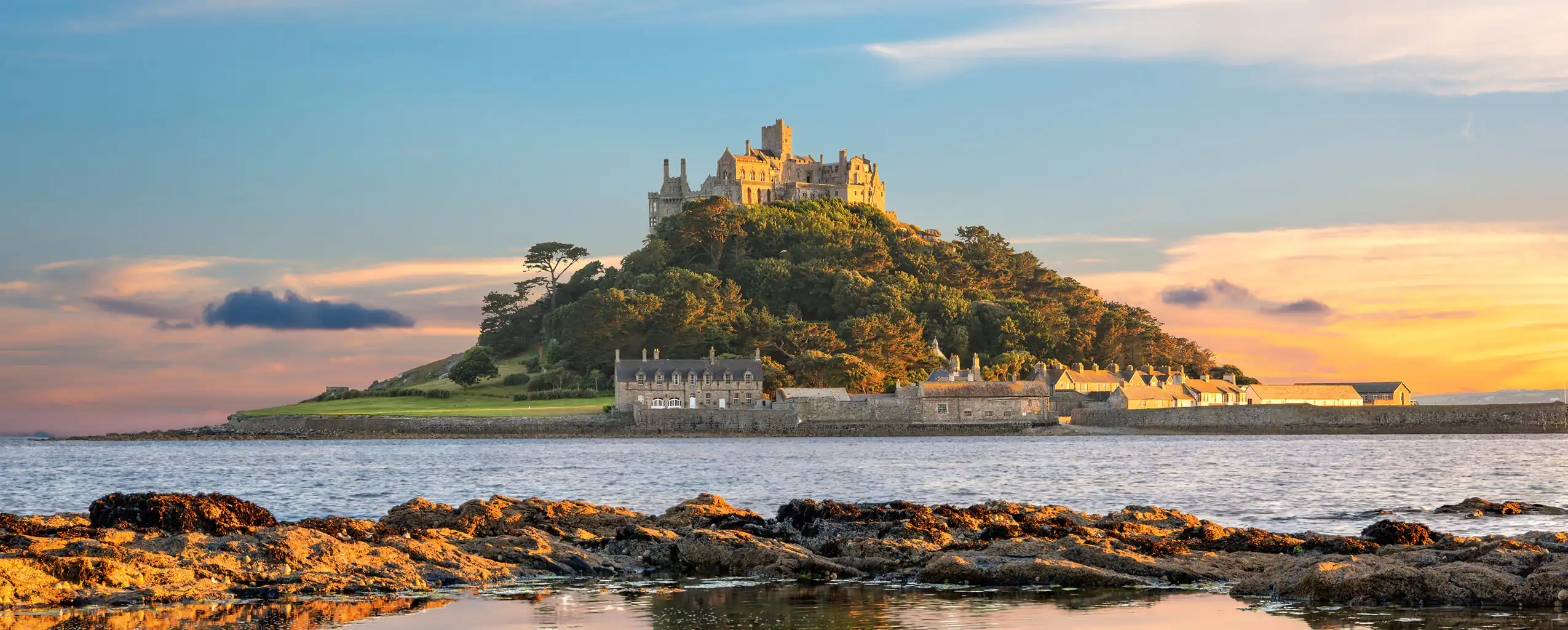 Sunset over St Michael's Mount near Marazion, Cornwall, highlighting its silhouette against a vibrant sky, evoking a serene atmosphere.