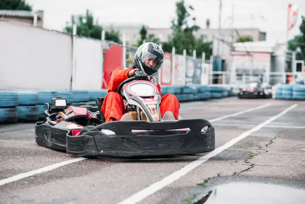A man in an orange suit speeds around a go-kart track in Cornwall, showcasing a great adventure seekers activity in Cornwall.