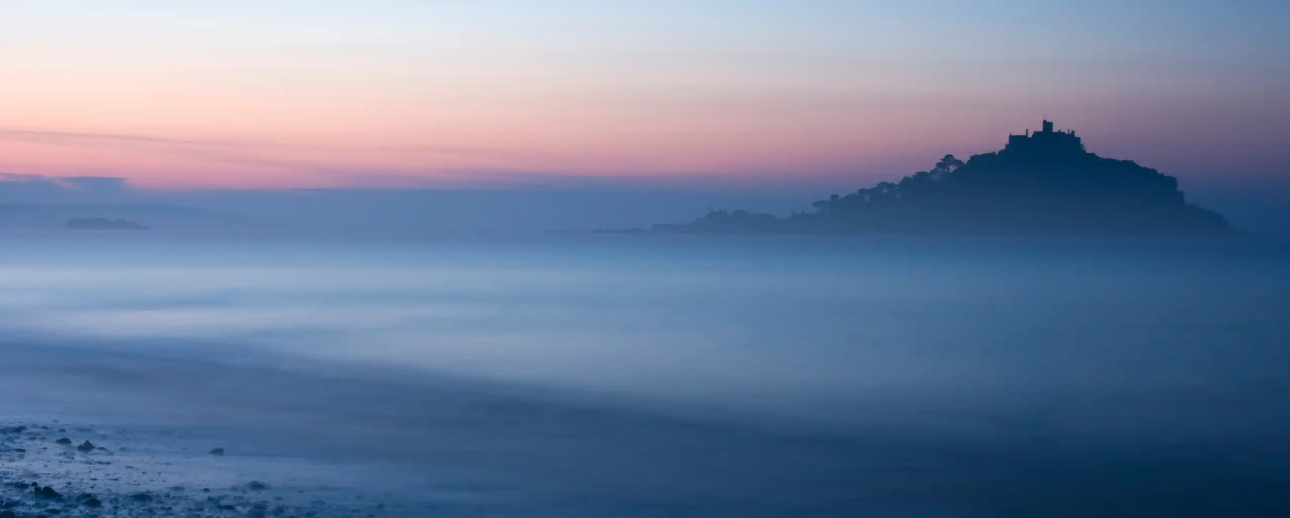 Misty sunrise at St Michael's Mount in Marazion, Cornwall, with fog enveloping the historic island, a great piece of Marazion arts and heritage.