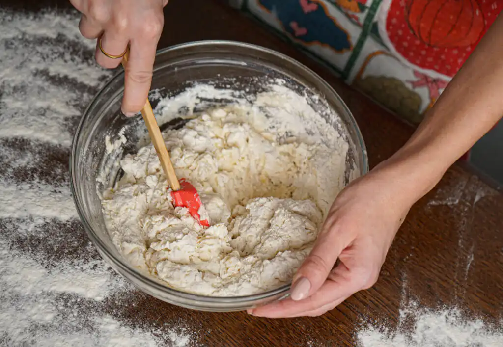 A person mixing dough in a bowl at St Ives Cookery School, showcasing a great thing to do this September in Cornwall.