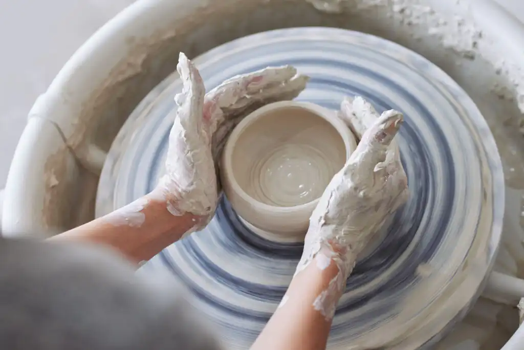 A person shaping clay on a potter's wheel during a workshop at Leach Pottery in St Ives, a great thing to do in Cornwall in September.