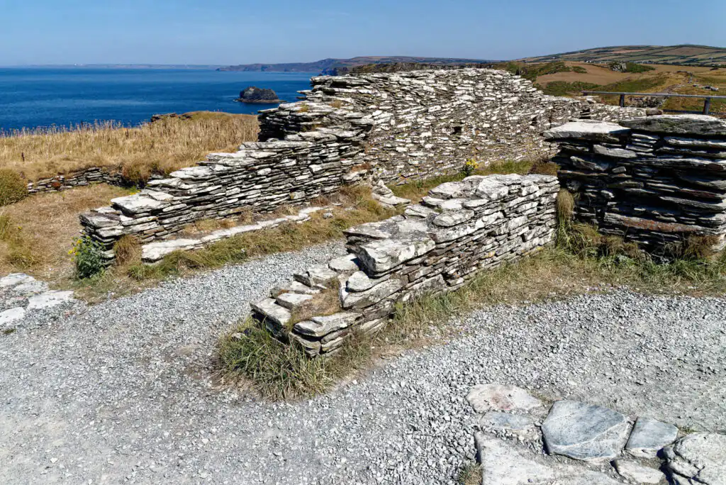 Ruins of Tintagel Castle with stone walls, gravel paths, and a view of the ocean and cliffs in the background, a great historic site in Cornwall.