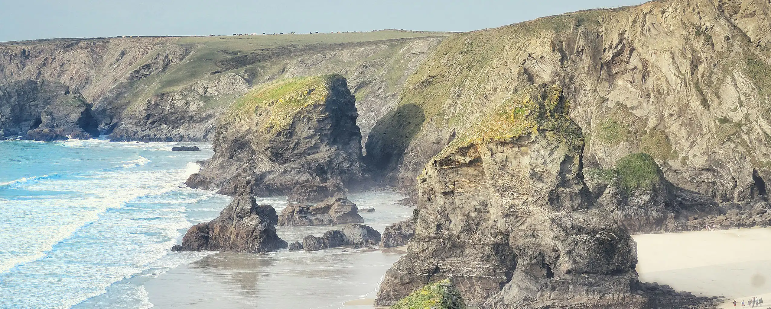 Majestic rock formation at Bedruthan Steps, overlooking the beach near Mawgan Porth, surrounded by crashing waves.