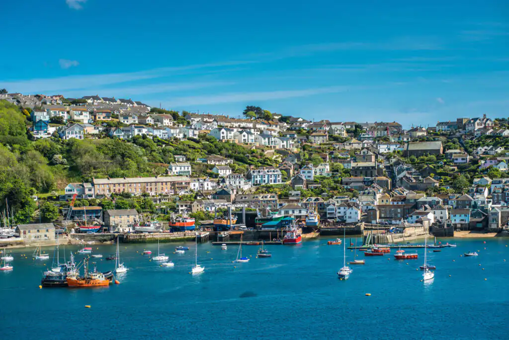 A clear blue sky dotted with fluffy white clouds above Fowey Harbour, highlighting a beautiful day for walking in Cornwall.