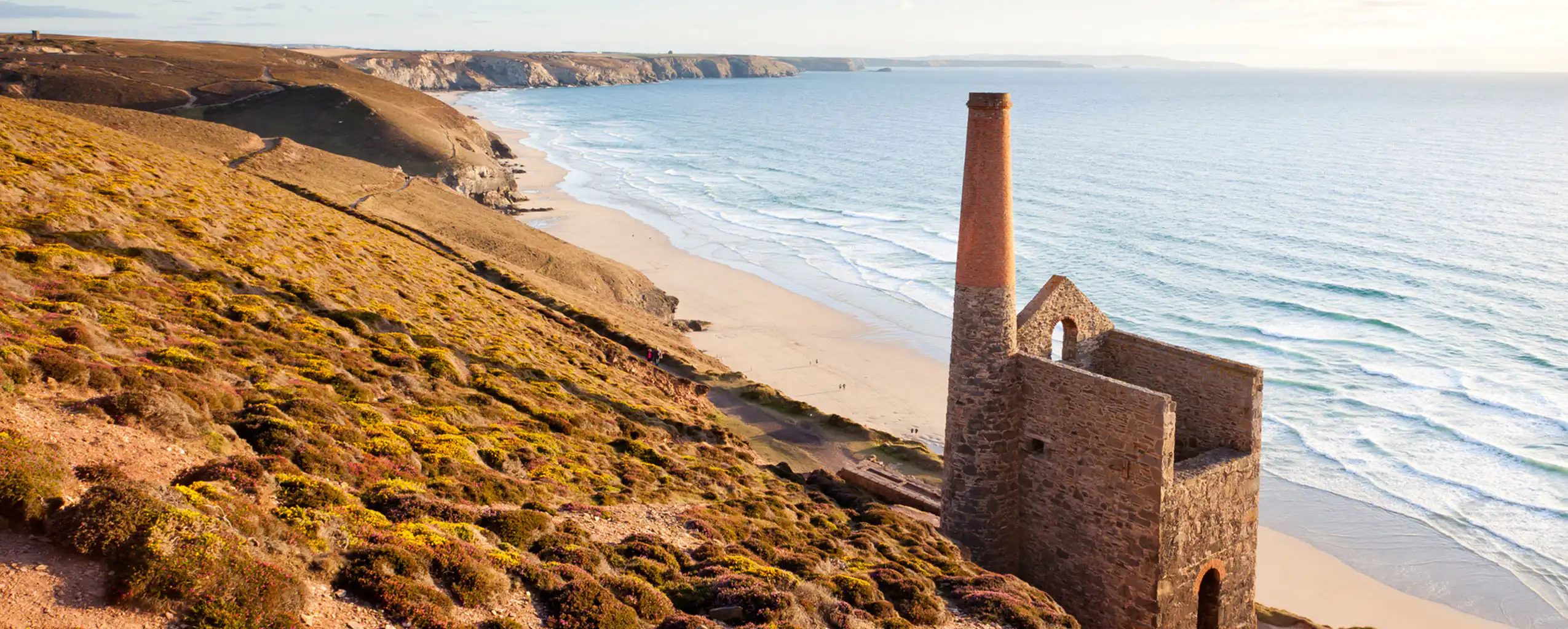 Ruins of Towanroath Engine House perched on a hillside near St Agnes, surrounded by lush greenery and scenic views, a key part of St Agnes' heritage.