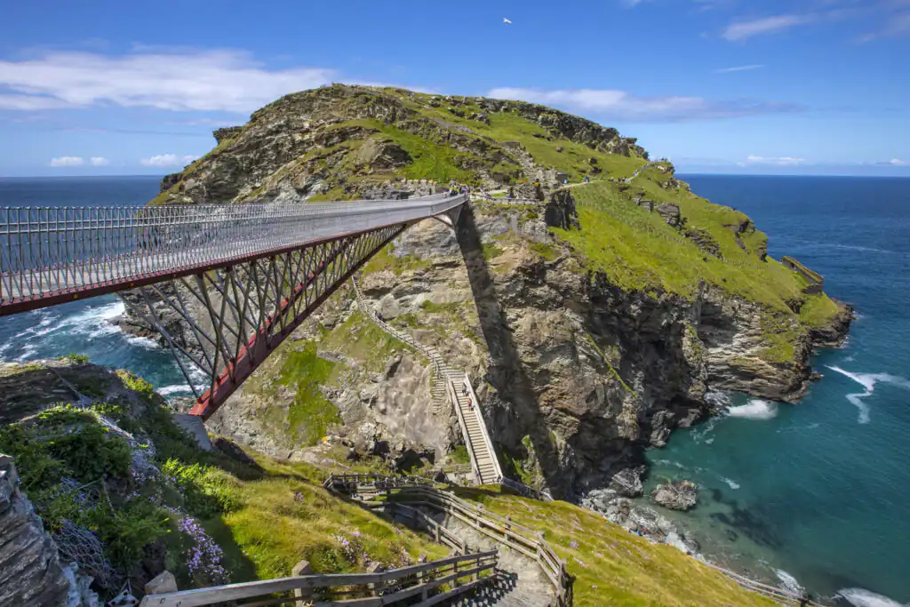 A scenic bridge spans the ocean, perched on a cliff near Tintagel Castle, perfect for a family day out in Cornwall.