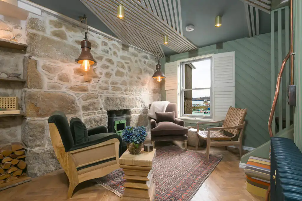 Cosy living room featuring a stone wall and a fireplace at She Sells Sanctuary, perfect for family celebrations in Cornwall.