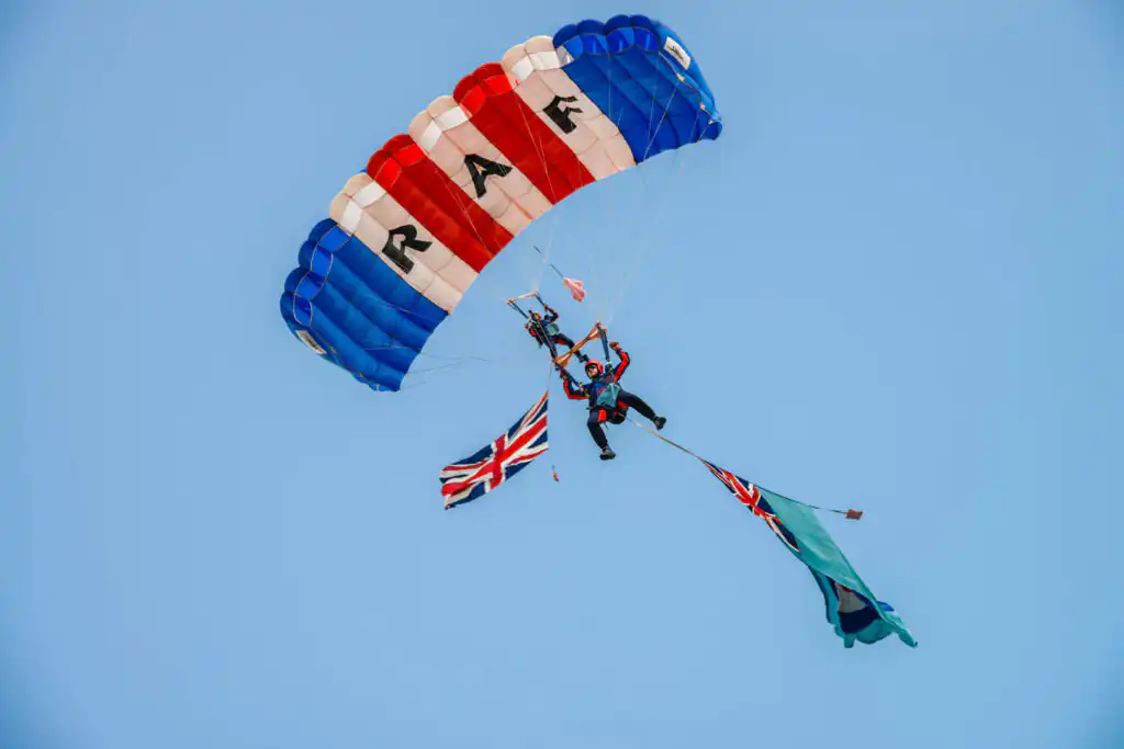 Two people fly a British flag and a red, white, and blue parachute at the Royal Cornwall Show, a Cornish summer festival.