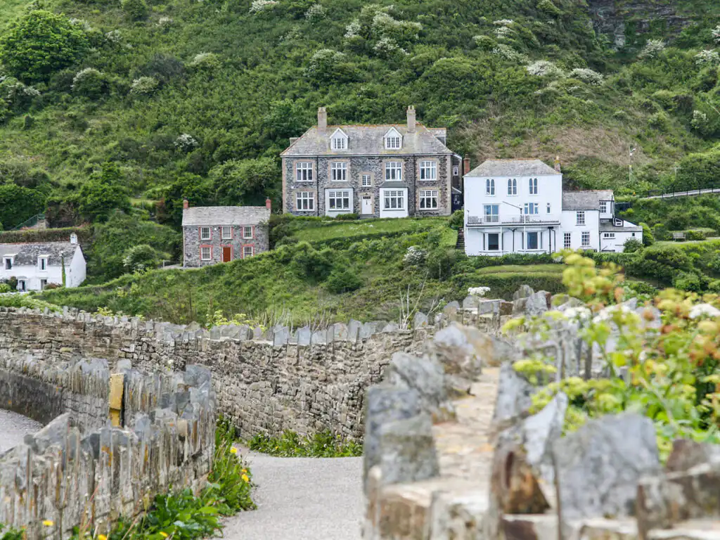 A scenic path leads to the iconic Doc Martin Cottages, nestled against a stone wall on a hillside in Port Isaac, a key part of Port Isaac's arts and heritage.