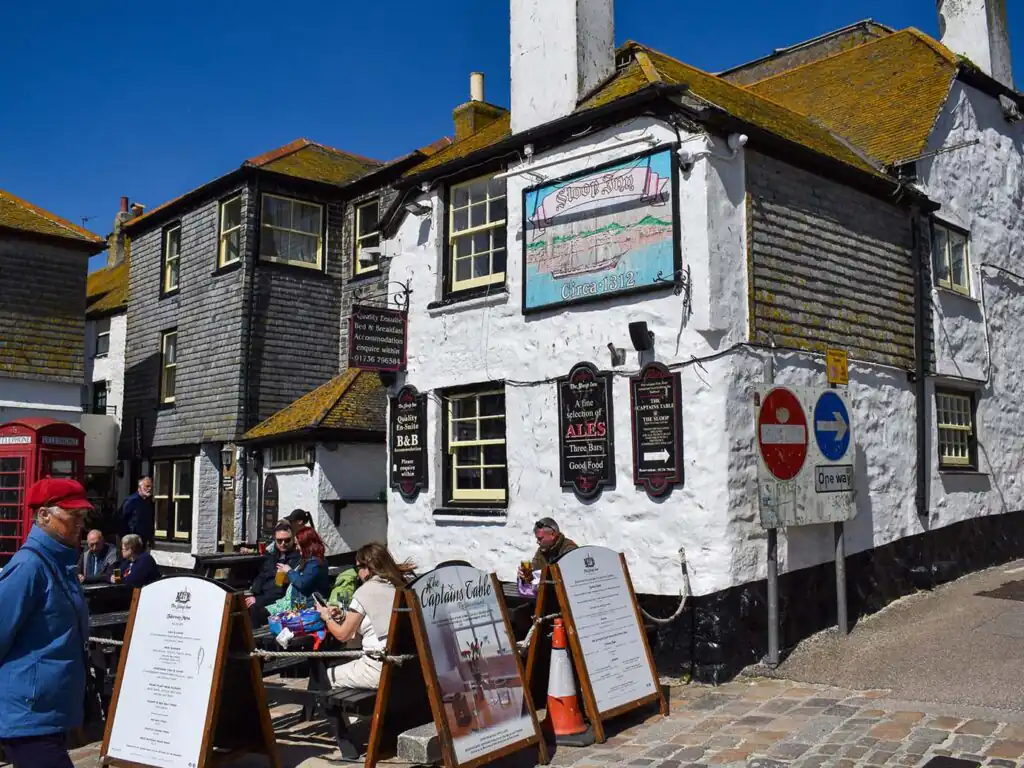 The Sloop St Ives, a white structure topped with a black roof, inviting visitors to enjoy its food and drink offerings.