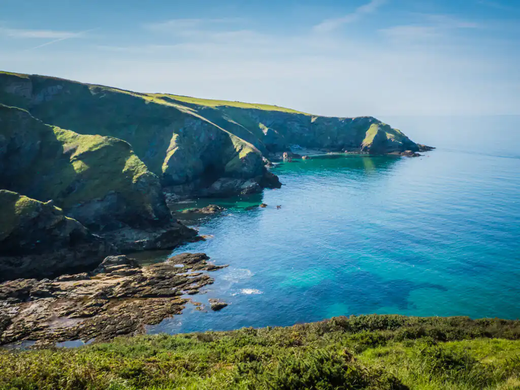 Panoramic vista of the ocean and steep cliffs from a hill near Port Isaac, highlighting the area's stunning landscape, a great thing to see and do in Port Isaac.