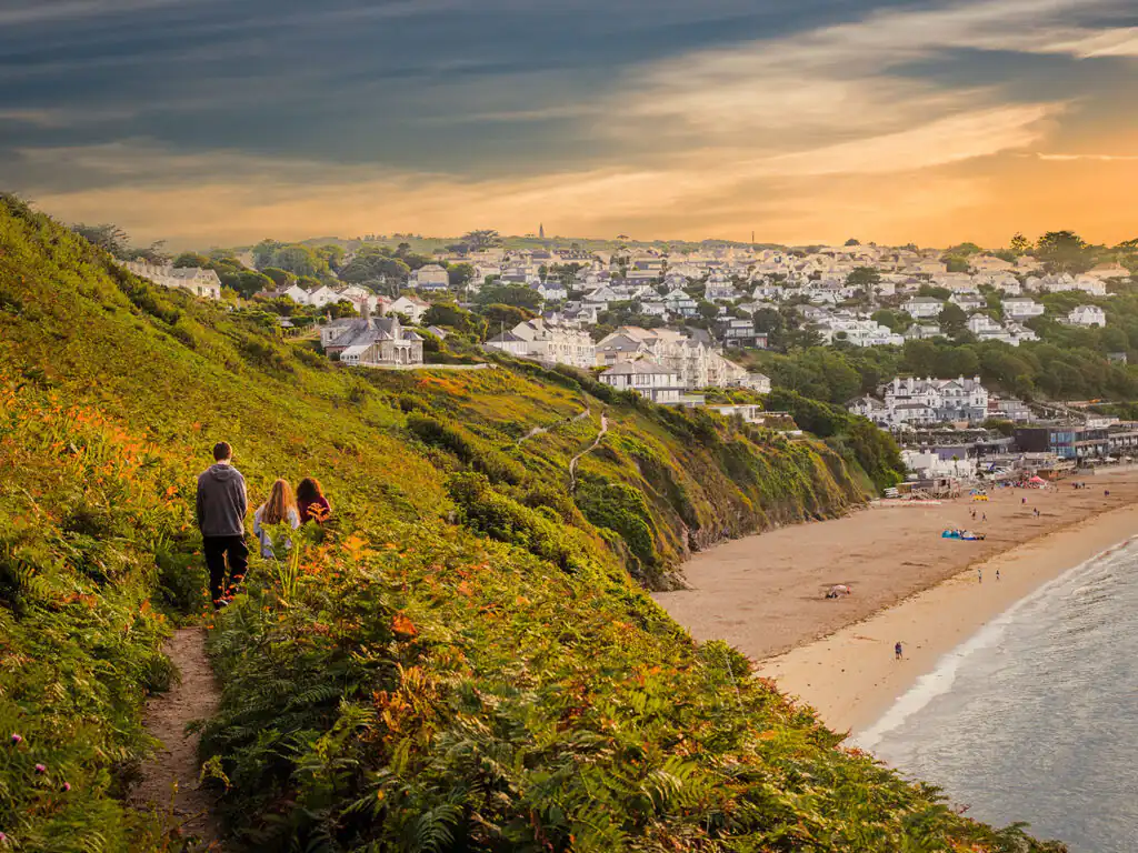 A family enjoy a peaceful moment on a coastal path, overlooking the stunning beach at Carbis Bay.
