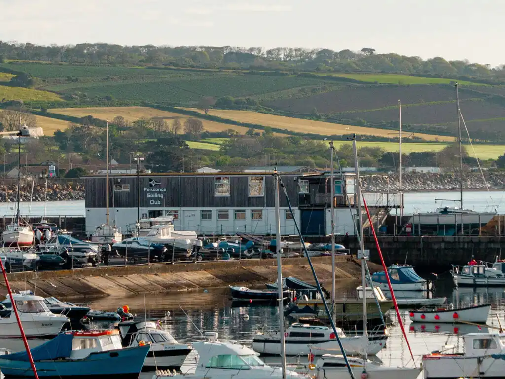 A scenic view of Penzance Harbour, showcasing a large body of water with boats and coastal scenery, a great place for food and drink in Mount's Bay.