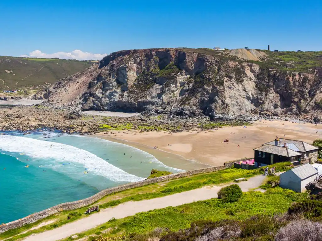 Scenic Trevaunance Cove beach with a charming house nestled on the shoreline, surrounded by cliffs and clear blue waters, a great piece of arts and heritage in St Agnes.