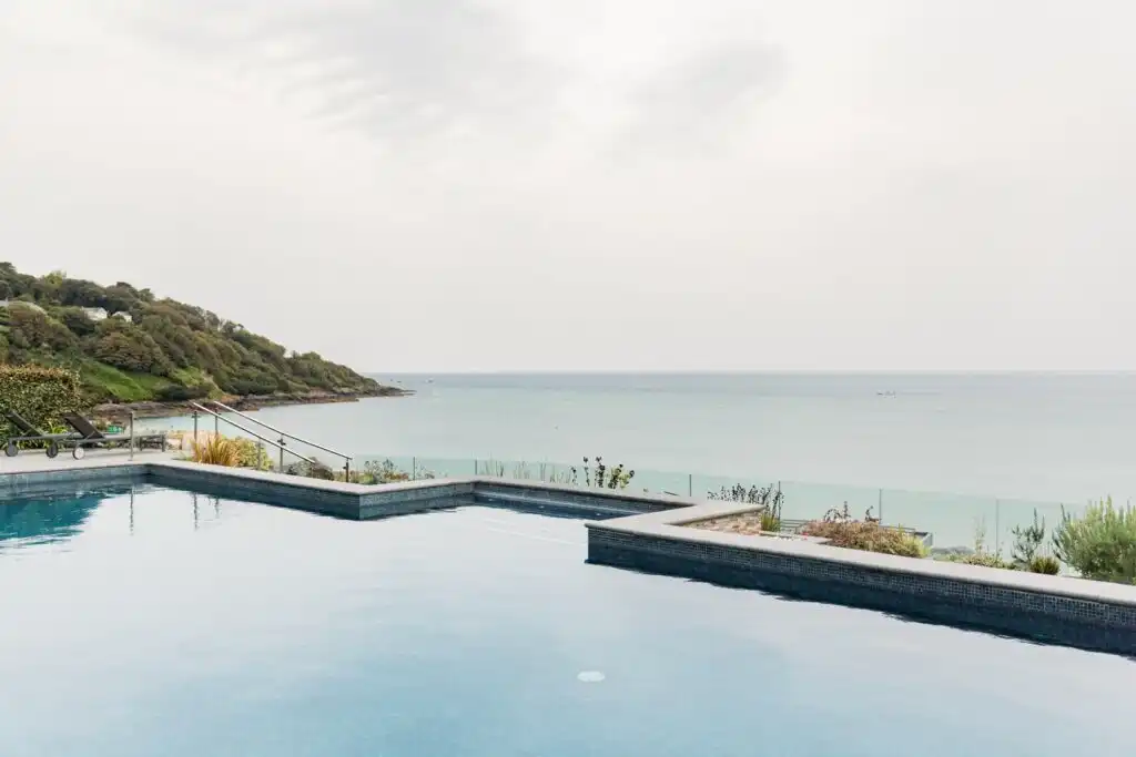 A serene pool at Carbis Bay Estate Spa, with stunning ocean views and a clear blue sky in the background, a must do when planning a Carbis Bay Holiday.