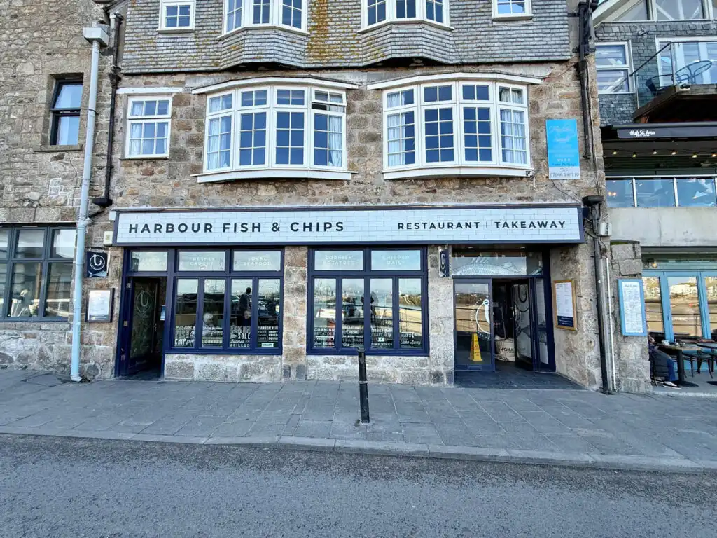 Front view of Harbour Fish and Chips restaurant in St Ives, featuring a prominent sign with the restaurant's name, home to some of the best fish and chips in Cornwall.