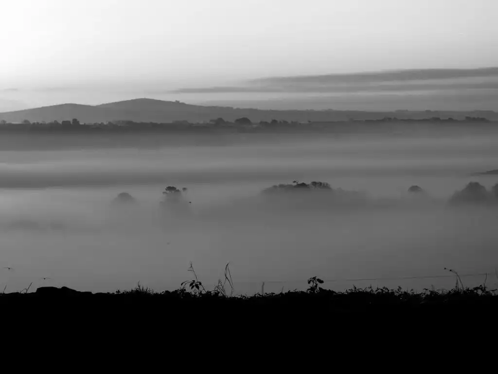 Foggy black and white landscape of hills overlooking Carbis Bay, creating a serene and mysterious atmosphere, a must visit when planning a holiday in Carbis Bay.