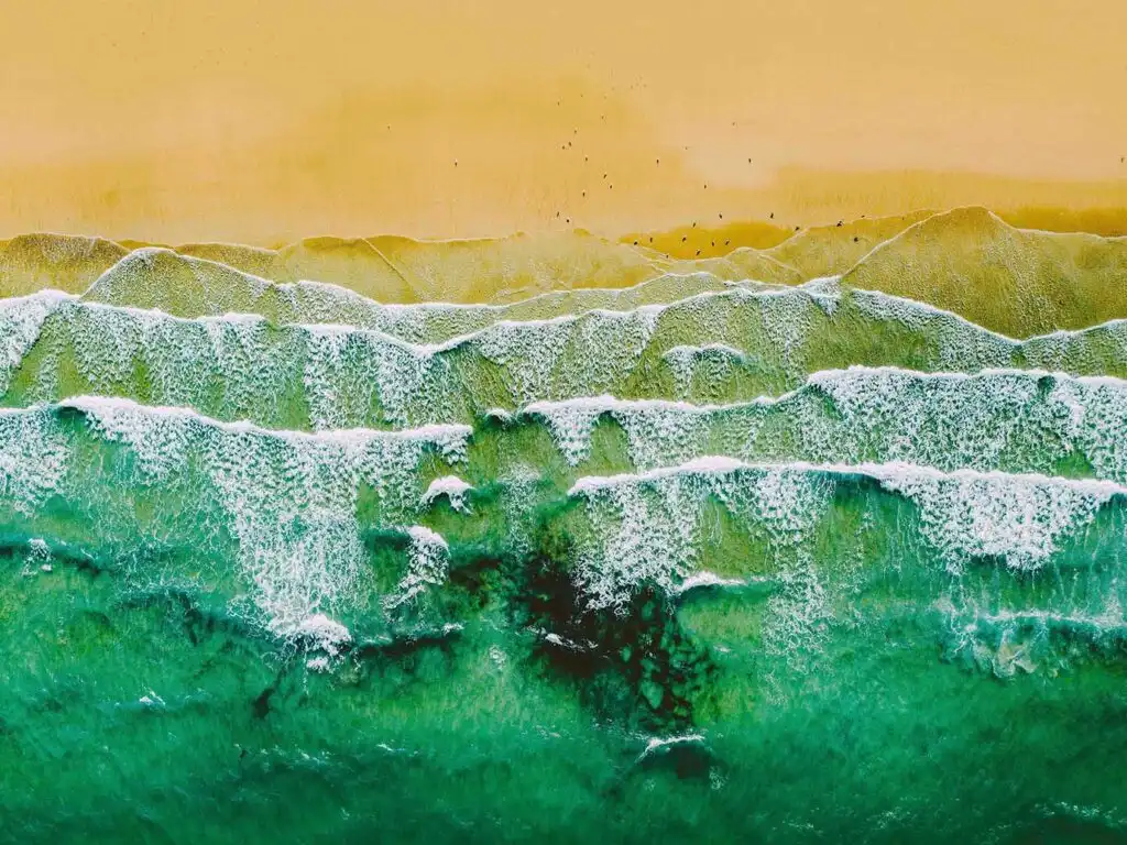 Aerial view of Carbis Bay Beach, showcasing the ocean waves gently rolling onto the sandy shore, a must do when planning a Carbis Bay Holiday.
