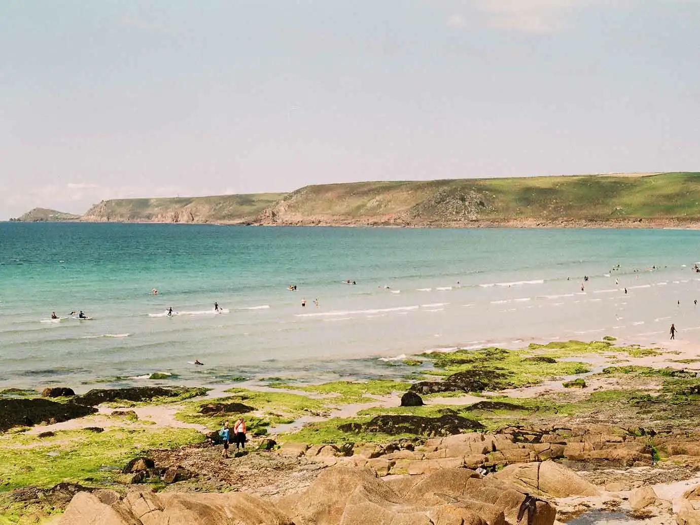 Vibrant beach at Sennen in Cornwall, with children playing and waves lapping at the shore.