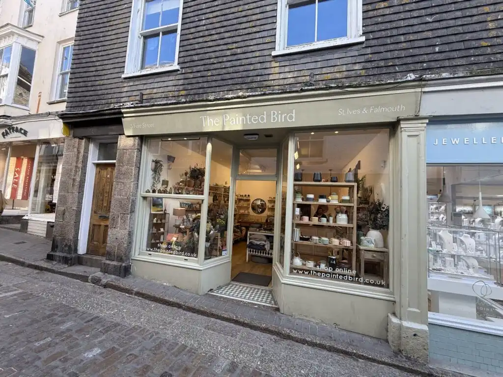 Charming shop front of The Painted Bird in St Ives, showcasing a colourful window display of unique items for sale, a great independent shop in St Ives.