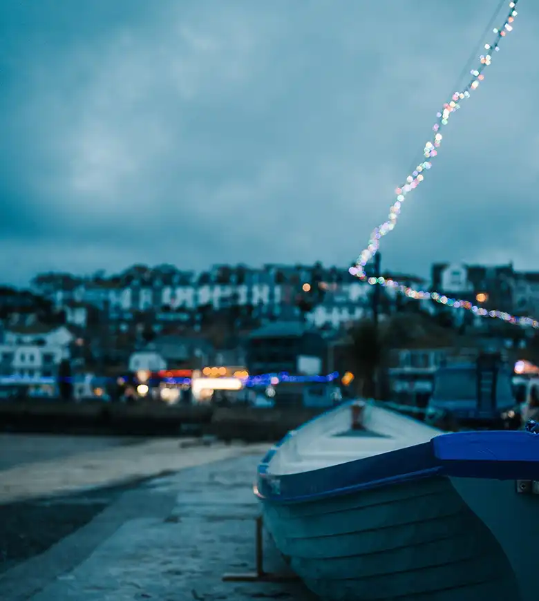 A boat rests on the harbour wall of St Ives Harbour, surrounded by festive Christmas decorations in Cornwall, a great place to explore from a Cornwall holiday cottage