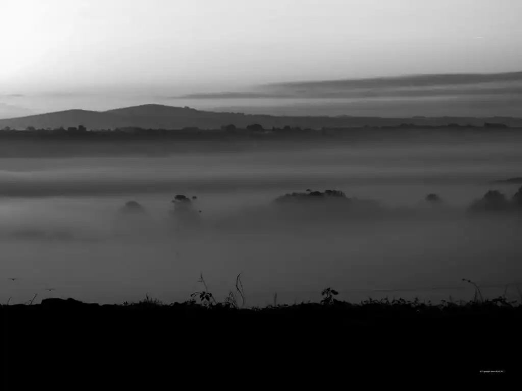 Black and white photo of a foggy Trencrom Hill, showcasing the serene landscape of Carbis Bay and Lelant in Cornwall, a great place to walk from Carbis Bay.